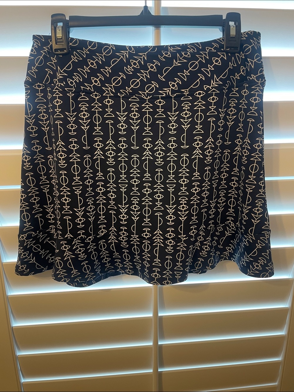 Golftini Zodiac skort features navy and white geometric print and ruffle hem.